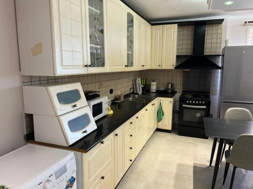 a kitchen with white cabinets and black appliances at SKetch Apartments 2 in Durrës