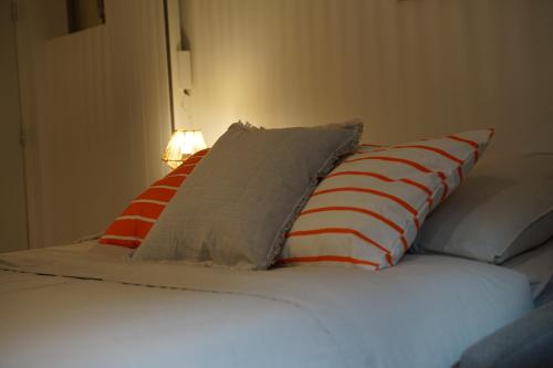 a bed with four pillows on top of it at Studio cosy Eglise Notre-Dame-des-Calades in Villefranche-sur-Saône