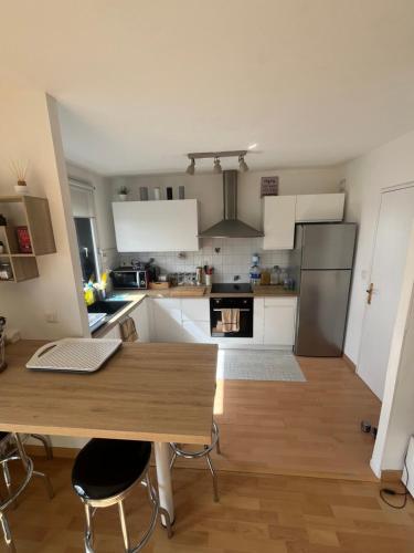 uma cozinha com armários brancos e uma mesa de madeira em Appartement 6 personnes Lille em Lille