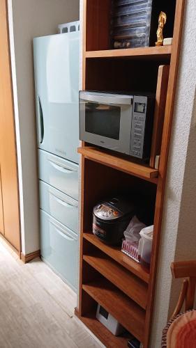 a microwave in a cabinet next to a refrigerator at Stage YOU in Tokyo