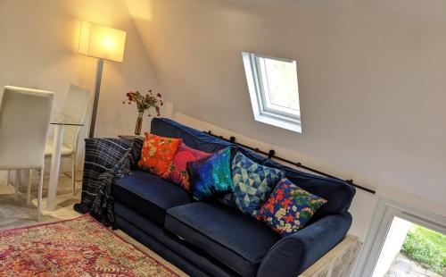 a blue couch with colorful pillows in a living room at Small apartment in the heart of Selsdon! in Addington