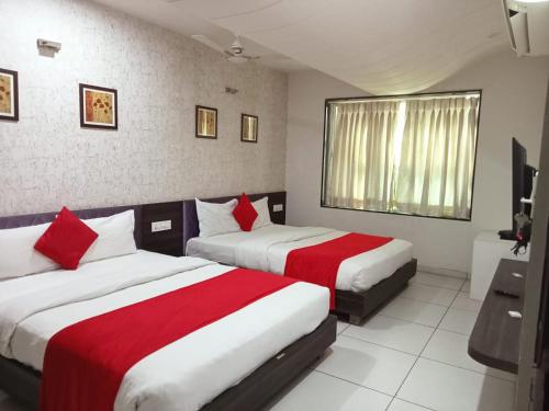 a bedroom with two beds with red and white sheets at Hotel Best Velly in Gandhinagar