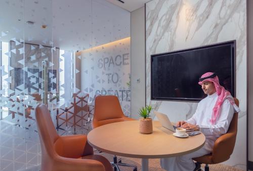 a woman sitting at a table with a laptop at Onyx Rotana in Manama