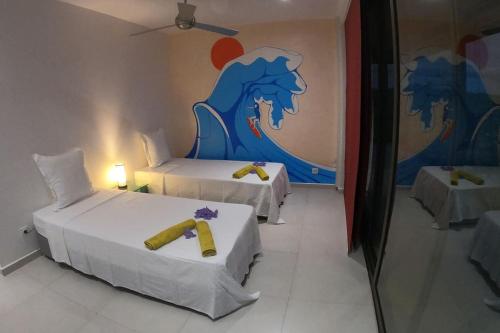 a room with two beds and a painting on the wall at La Canopée vue sur mer in Nosy Be