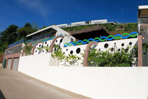a white building with a hill on top of it at La Canopée vue sur mer in Nosy Be