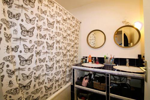 a bathroom with two sinks with butterflies on the wall at CARBAU Maisonnette pour 8 personnes dans une résidence privée avec piscine à Carqueiranne in Carqueiranne