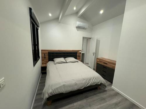 een slaapkamer met een bed in een witte kamer bij Appartement neuf 2 chambres 8 Couchages 