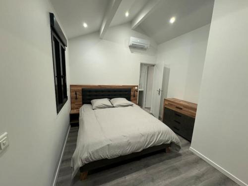 une chambre avec un lit dans une pièce blanche dans l'établissement Appartement neuf 2 chambres 8 Couchages, à Les Alluets-le-Roi