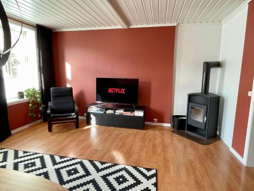 a living room with a tv and a wood stove at Sentral og fargerik bygårdsleilighet in Halden