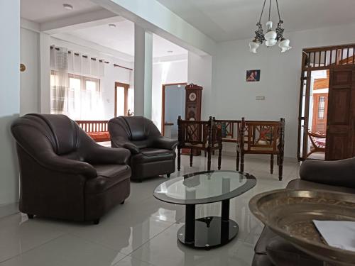 a living room with leather chairs and a table at Richland's Villa in Kandy