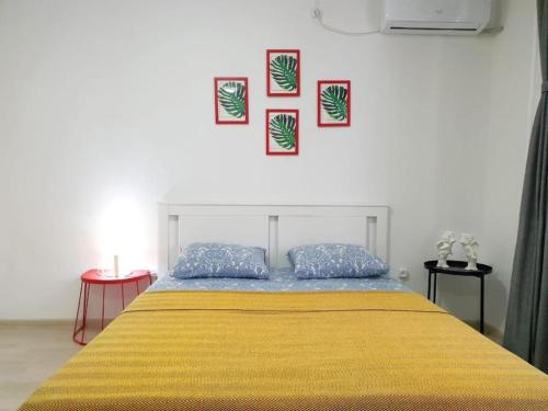 a bedroom with a yellow bed with three pictures on the wall at Милая Студия 2 in Atyrau