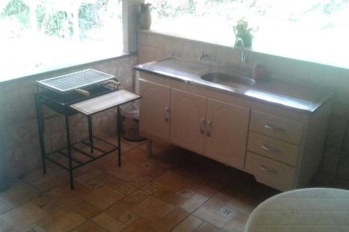 cocina con fregadero, mesa y ventana en Recanto beira rio - Sao Pedro da serra. en Nova Friburgo
