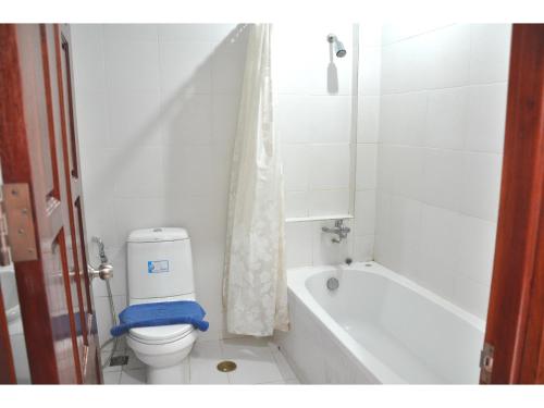 a white bathroom with a toilet and a bath tub at Highfive Guest House in Pattaya
