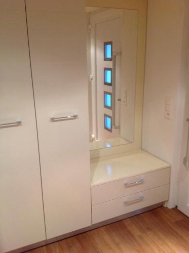 einen weißen Schrank mit einem Spiegel und einem Schrank in der Unterkunft GARDEN in Brienz