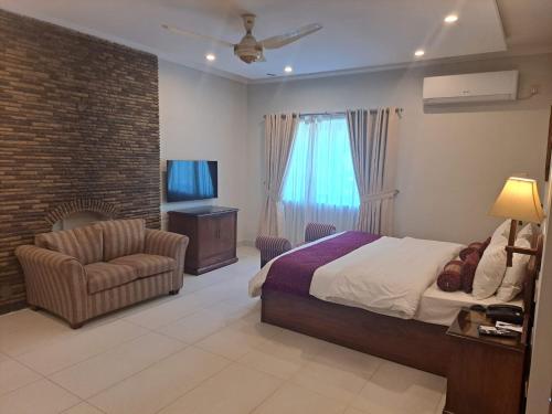 1 dormitorio con 1 cama, 1 silla y TV en Welcome Hotel Islamabad, en Islamabad