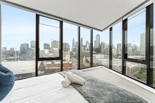 a bedroom with a bed and large windows at Skyline City Zen in Melbourne