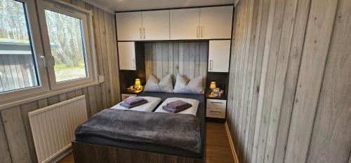a small bedroom with a bed and a window at Mobilheim Marine Glück im Yachthafen Peenemünde in Peenemünde