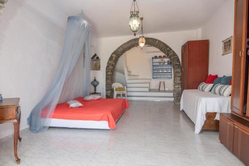 a bedroom with a red bed and an archway at Tinos Sunset Villa in Kékhros
