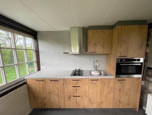 een keuken met houten kasten en een wastafel bij Vakantiewoningen 'Hoeve de Witte Olifant' in Noorbeek