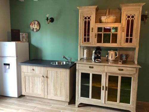 a kitchen with wooden cabinets and a white refrigerator at Le Petit Paradis de Marcelise in Le Ponchel