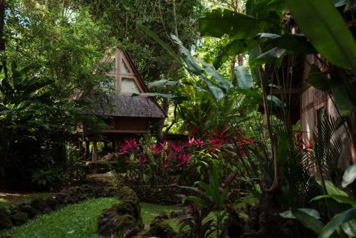 a garden in front of a house with pink flowers at Roots Tree House in Uluwatu