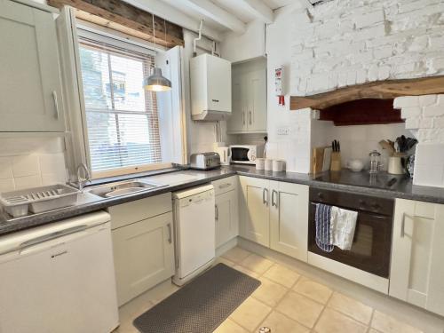 a kitchen with white cabinets and a brick wall at 10 Mill Road in Padstow