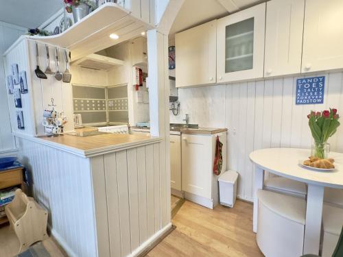 a small kitchen with white cabinets and a table at Little Penty in Padstow