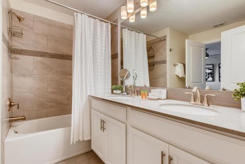 ein Badezimmer mit zwei Waschbecken, einer Badewanne und einer Dusche in der Unterkunft 4808 LL Magical 4BR Disney Townhome Pool in Kissimmee