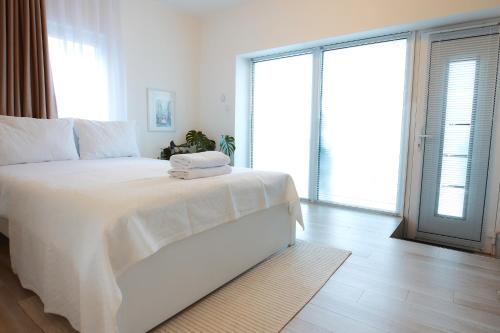a white bedroom with a large bed with towels on it at PRIMA APARTMENTS in Satu Mare