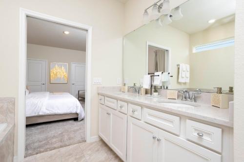 baño con lavabo, espejo y cama en 2330 LC - Luxurious 8BR Townhome Getaway, en Davenport