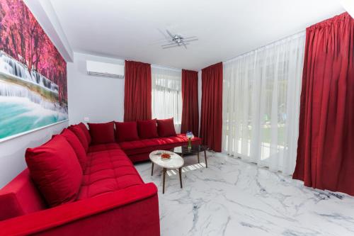 a red couch in a living room with red curtains at ENEVI Guest Houses-Къщи за гости Еневи in Sandanski
