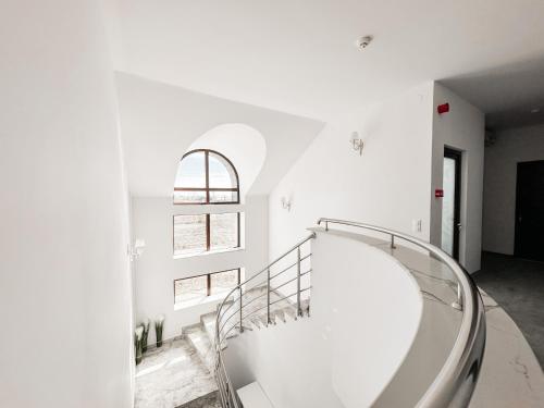 a spiral staircase in a white room with a window at Complex Vila Rania in Satu Mare
