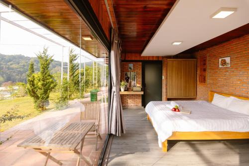 a bedroom with a bed and a large window at Scent Bungalow - Village in Da Lat