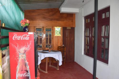 a coca cola sign in a room with a table at Blue Bed Hostel in Nanu Oya