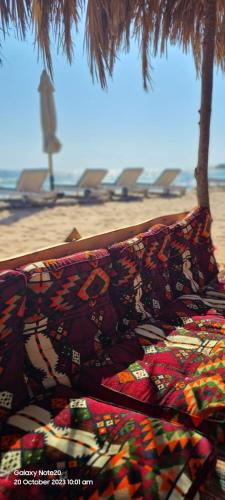 a pile of blankets on a beach with a palm tree at Panorama Lodge Nuweiba in Nuweiba