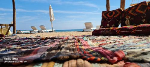 a blanket on a beach with chairs and the ocean at Panorama Lodge Nuweiba in Nuweiba