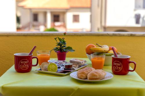a table with a plate of food and two cups of orange juice at Sardinia rooms in Alghero