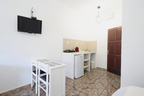 a white kitchen with a counter and a table at Aphroditi Hotel in Leipsoi