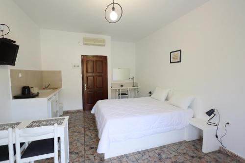 ein weißes Schlafzimmer mit einem weißen Bett und einem Schreibtisch in der Unterkunft Aphroditi Hotel in Lipsi