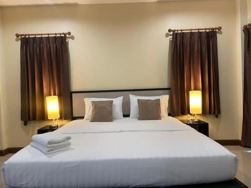 a bedroom with a large white bed with two lamps at Pak Ping Rim Khong in Chiang Saen