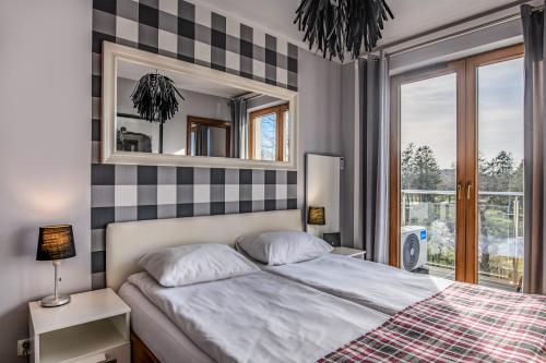 a bedroom with a bed with a mirror and a window at Apartament Stonehaven in Jastrzębia Góra