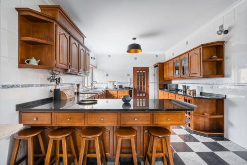 a large kitchen with wooden cabinets and bar stools at GuestReady - Quinta do Sol in Mealhada