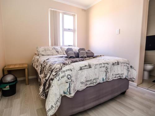 a bedroom with a bed with a blanket and a window at Villa on Maxi in Velddrif