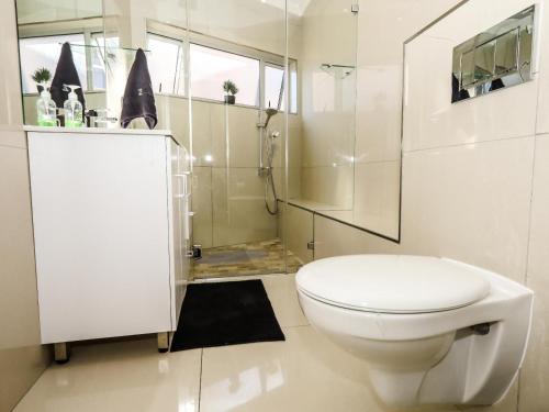 a white bathroom with a toilet and a shower at Villa on Maxi in Velddrif