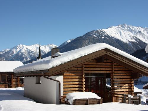 a cabin covered in snow with mountains in the background at Luxurious chalet with sauna in K nigsleiten in Wald im Pinzgau