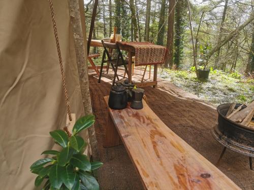 a porch of a tent with a table and a chair at Sweet Hill Eco Fort in Exeter