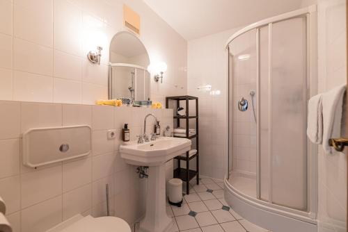 La salle de bains blanche est pourvue d'un lavabo et d'une douche. dans l'établissement Ferienwohnung Suite-Mathilda, à Reit im Winkl