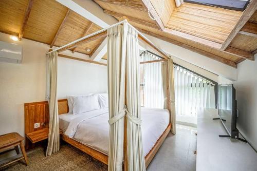 ein Schlafzimmer mit einem Himmelbett in einem Zimmer in der Unterkunft The Putih Tiny Villa - Stylish Mezzanine Loft 5mins to Nyanyi Beach in Tanah Lot