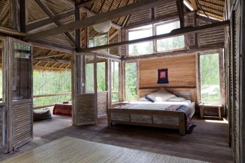 una camera da letto in una casa sull'albero con un letto e finestre di MaoMeno Yoga Resort a Gili Meno