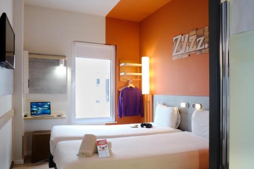 a hotel room with two beds and a window at Ibis Budget Bilbao City in Bilbao